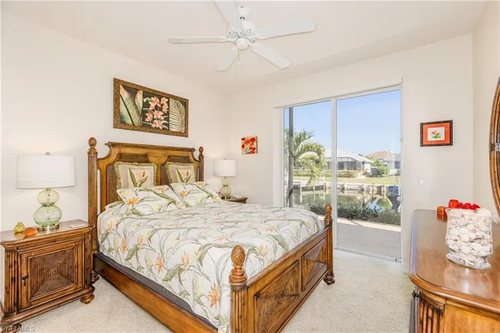 Bedroom with access to exterior, light colored carpet, and a ceiling fan