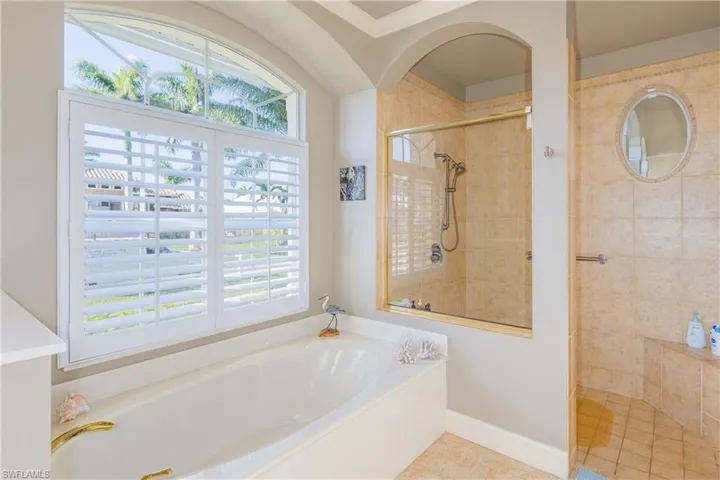 Bathroom with a garden tub, baseboards, a tile shower, and tile patterned floors