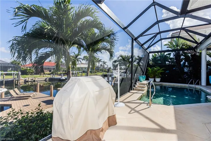 Outdoor pool featuring a lanai, a boat dock, grilling area, and a patio