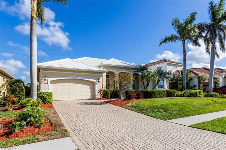Mediterranean / spanish-style house with decorative driveway, stucco siding, an attached garage, a front yard, and a tiled roof