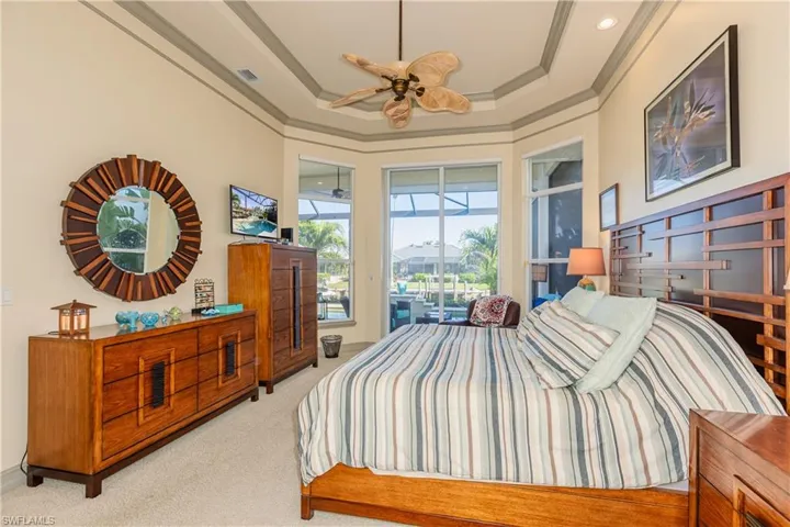 Bedroom featuring visible vents, access to exterior, a tray ceiling, crown molding, and carpet flooring