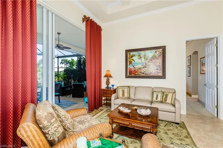 Tiled living room featuring arched walkways, ornamental molding, a ceiling fan, and baseboards