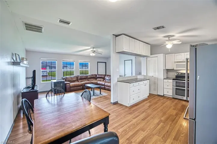 Kitchen with white cabinetry, light hardwood / wood-style flooring, appliances with stainless steel finishes, backsplash, and ceiling fan