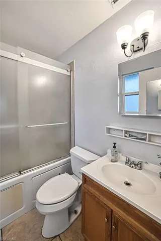 Full bathroom featuring tile flooring, vanity, toilet, and enclosed tub / shower combo