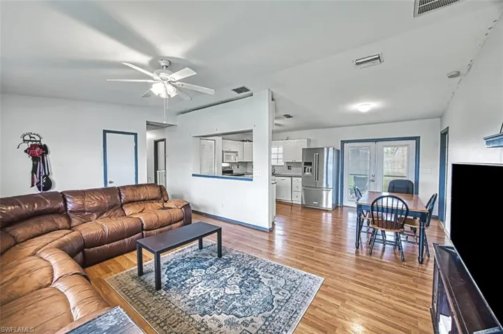 Living room with ceiling fan, light hardwood / wood-style floors, and french doors