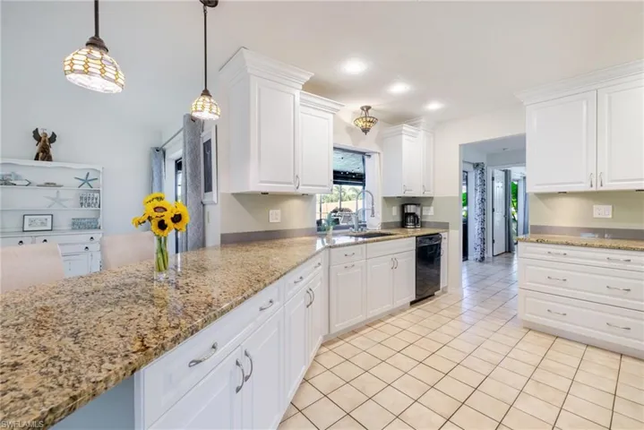 Kitchen with light tile patterned floors, white cabinets, light stone counters, and recessed lighting