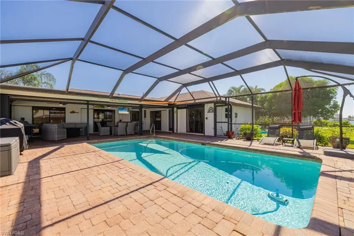 Outdoor pool with glass enclosure, an outdoor hangout area, a sunroom, and a patio