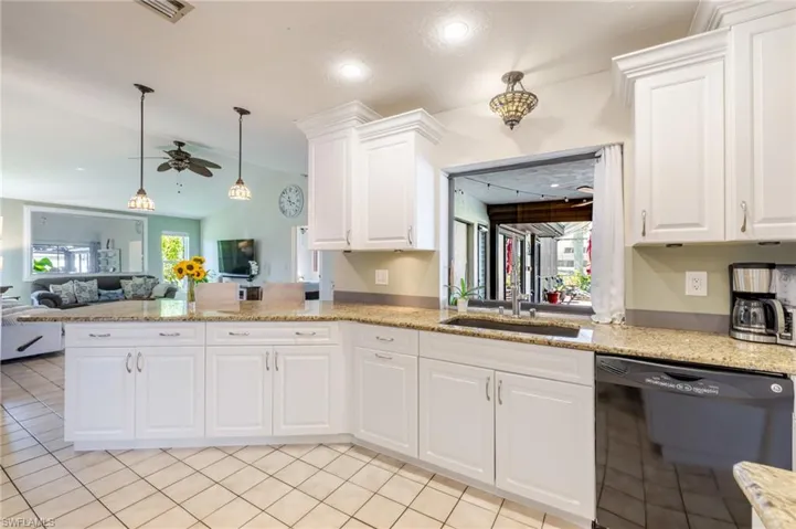 Kitchen featuring dishwasher, open floor plan, pendant lighting, white cabinetry, and lofted ceiling
