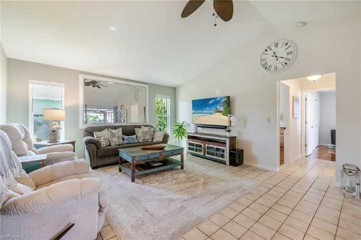 Living area with a ceiling fan, light tile patterned flooring, and high vaulted ceiling