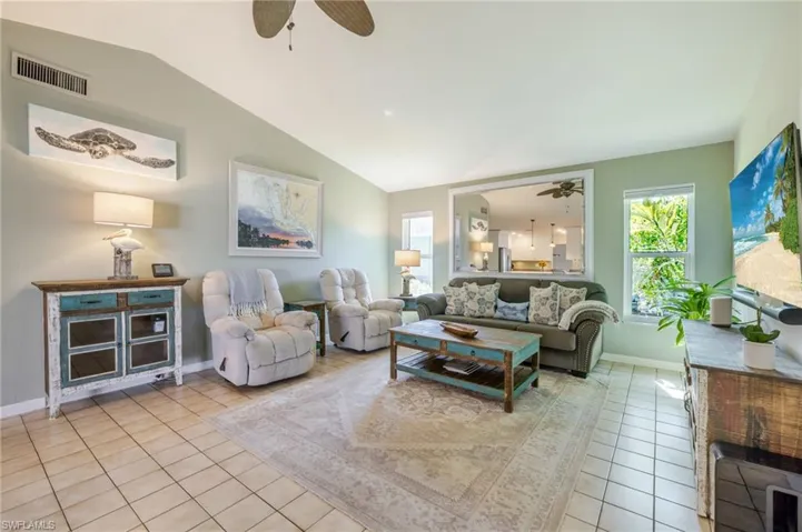 Living room featuring a ceiling fan, tile patterned floors, and lofted ceiling
