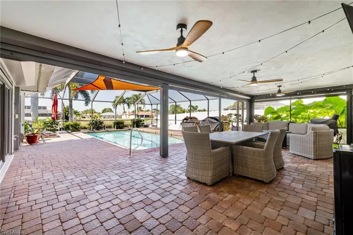 View of patio / terrace with ceiling fan, a sunroom, an outdoor pool, outdoor dining area, and a lanai