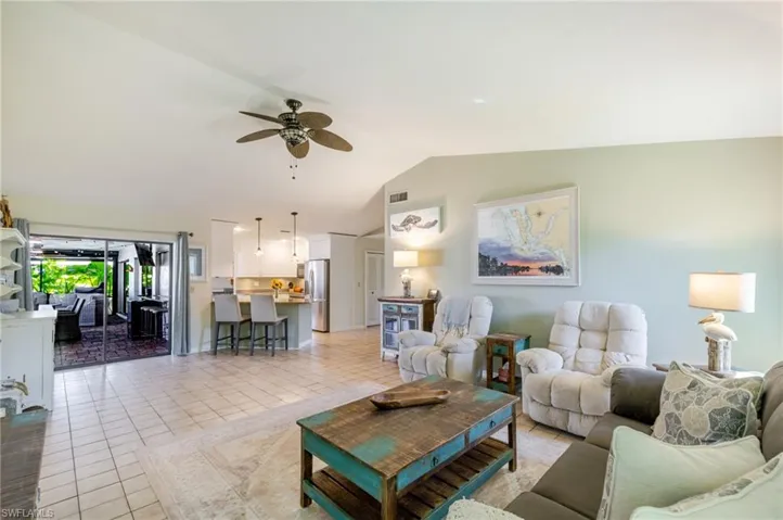 Living room featuring light tile patterned flooring, lofted ceiling, and ceiling fan