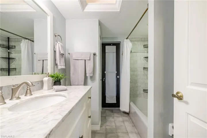 Full bathroom with vanity, light tile patterned floors, and shower / bath combination with curtain