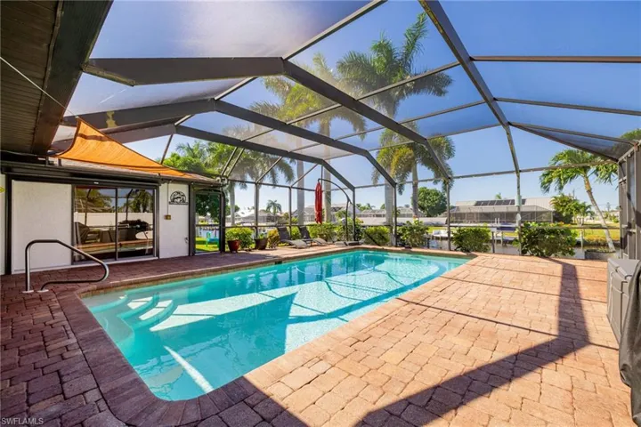 Outdoor pool featuring glass enclosure, a patio, and a sunroom