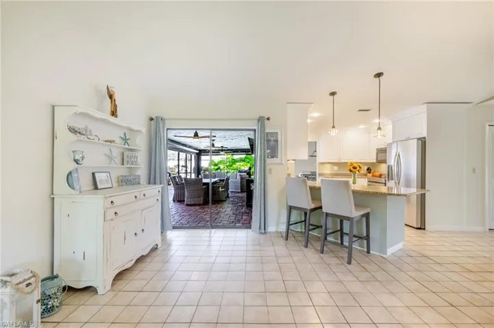 Kitchen with a breakfast bar, a peninsula, stainless steel appliances, white cabinetry, and hanging light fixtures