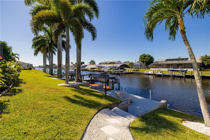 Dock area with a lawn, boat lift, a water view, and a residential view