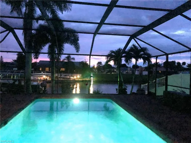 Pool at dusk featuring a lanai, an outdoor pool, and a sunroom