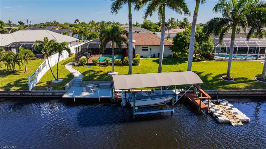 Dock area featuring boat lift, a yard, a water view, and a residential view