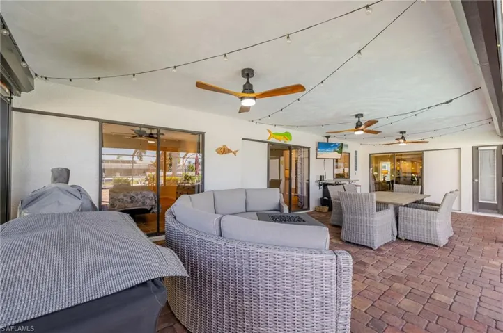 View of patio featuring outdoor dining space, ceiling fan, and an outdoor living space with a fire pit