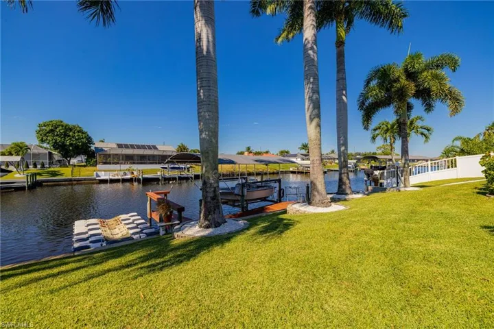 Dock featuring a lawn, boat lift, a water view, and a residential view