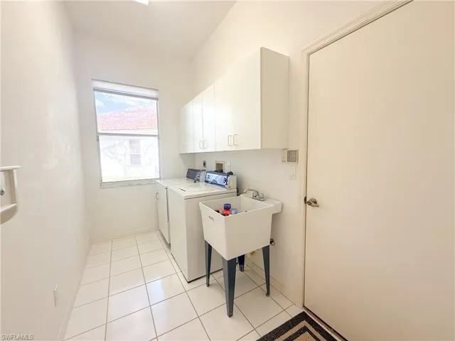 Clothes washing area featuring cabinets, independent washer and dryer, and light tile patterned floors