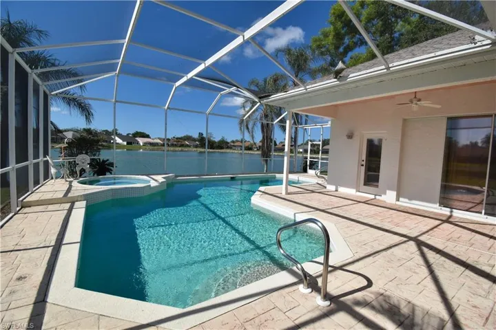 View of swimming pool with an in ground hot tub, a lanai, ceiling fan, a water view, and a patio area