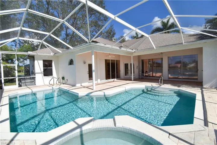 View of pool featuring a patio, an in ground hot tub, ceiling fan, and glass enclosure