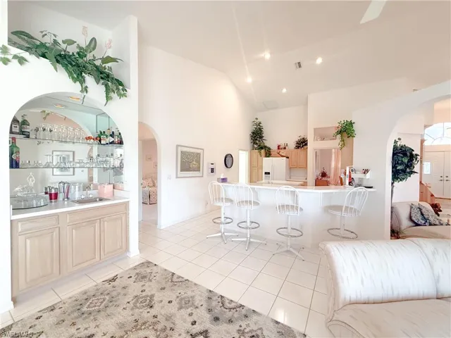 Kitchen with sink, a kitchen bar, white fridge with ice dispenser, light tile patterned floors, and light brown cabinets