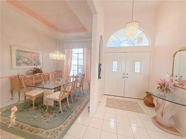 Tiled foyer entrance with a raised ceiling, a towering ceiling, and a chandelier