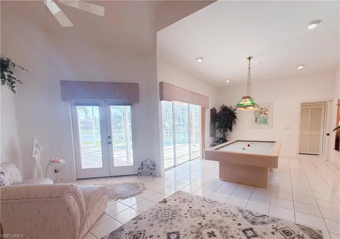 Recreation room featuring light tile patterned floors, pool table, french doors, and a high ceiling