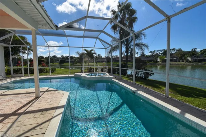 View of swimming pool with a lanai, an in ground hot tub, a patio, and a water view