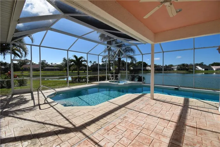 View of swimming pool featuring a patio, a water view, an in ground hot tub, and glass enclosure