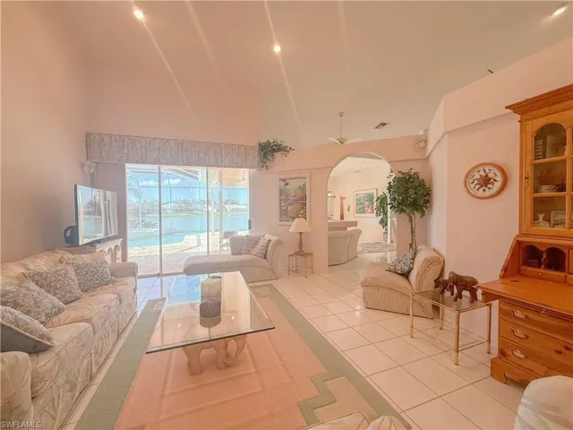 Tiled living room with ceiling fan and high vaulted ceiling