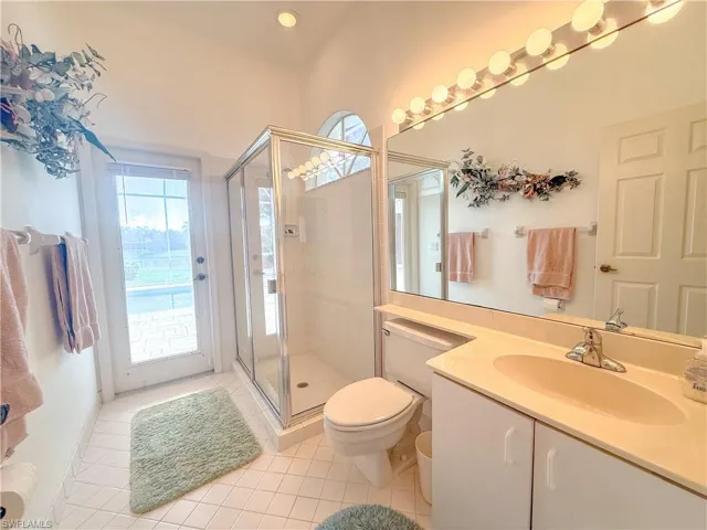 Bathroom with a shower with door, vanity, tile patterned floors, and toilet