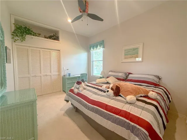 Carpeted bedroom with ceiling fan and a closet