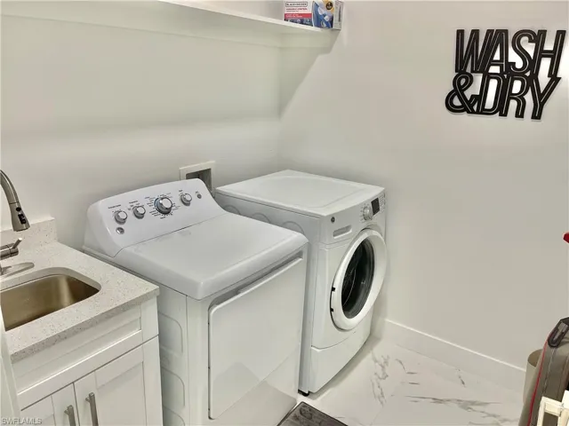 Washroom with cabinets, washing machine and dryer, and sink