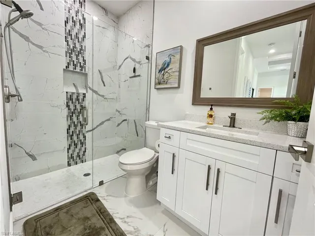 Bathroom featuring vanity, walk in shower, and toilet