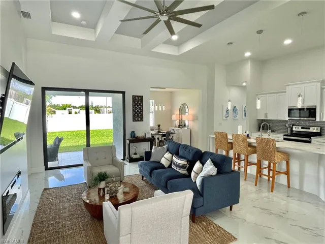 Living room featuring a towering ceiling, beamed ceiling, sink, coffered ceiling, and ceiling fan