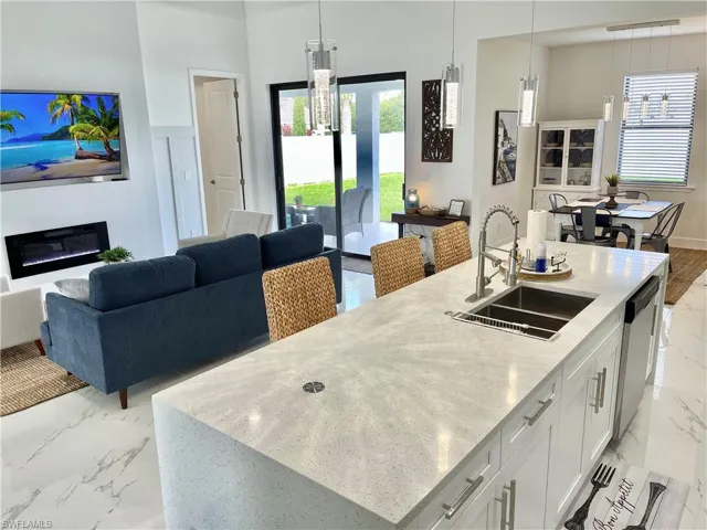 Kitchen featuring white cabinetry, decorative light fixtures, sink, and a center island with sink