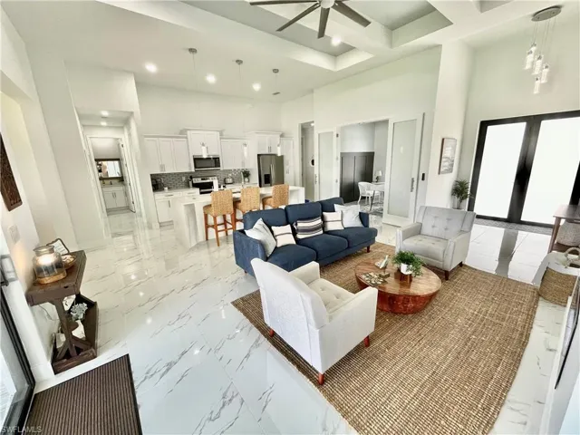 Living room featuring coffered ceiling, a towering ceiling, french doors, and ceiling fan