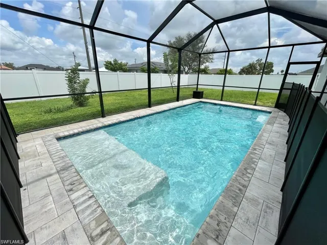 View of pool featuring a yard, a patio area, and glass enclosure