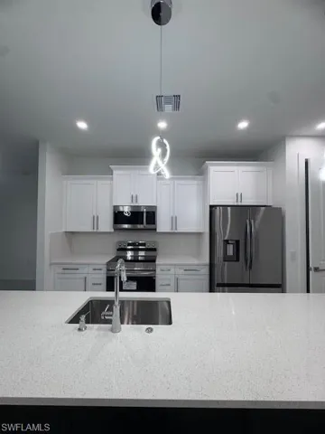 Kitchen featuring stainless steel appliances, a sink, visible vents, and white cabinets