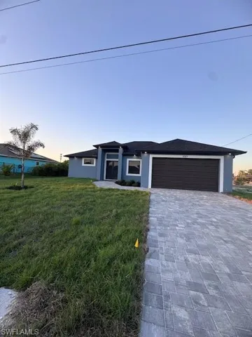 View of front of house with a garage and a yard