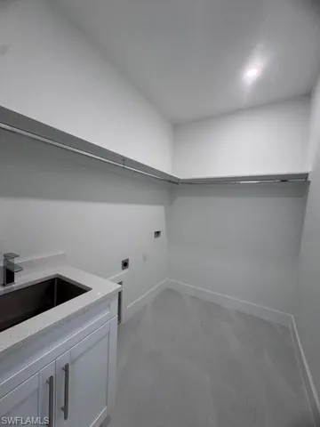 Laundry area with washer hookup, cabinet space, hookup for an electric dryer, a sink, and baseboards