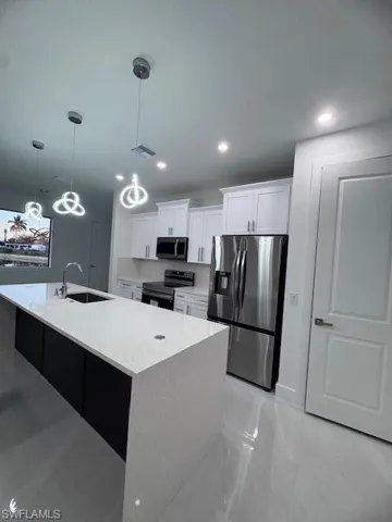 Kitchen with stove, a sink, white cabinetry, marble finish floor, and fridge