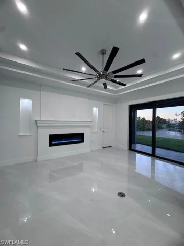 Unfurnished living room featuring ceiling fan and a tray ceiling
