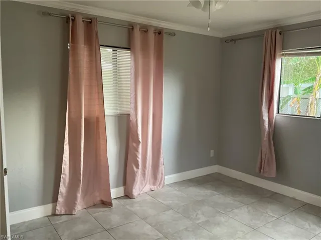 Spare room with ceiling fan, crown molding, and light tile floors