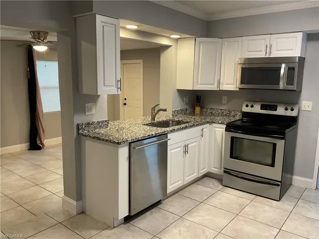 Kitchen featuring sink, crown molding, white cabinetry, and appliances with stainless steel finishes