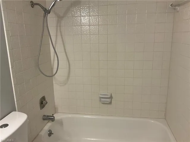 Bathroom featuring tiled shower / bath and toilet