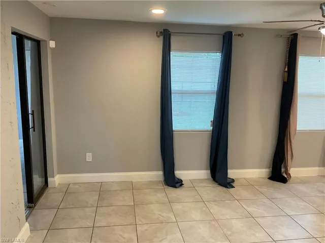 Empty room with ceiling fan and light tile floors
